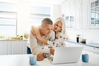 Senior couple looking at laptop together, discussing reverse mortgage information.